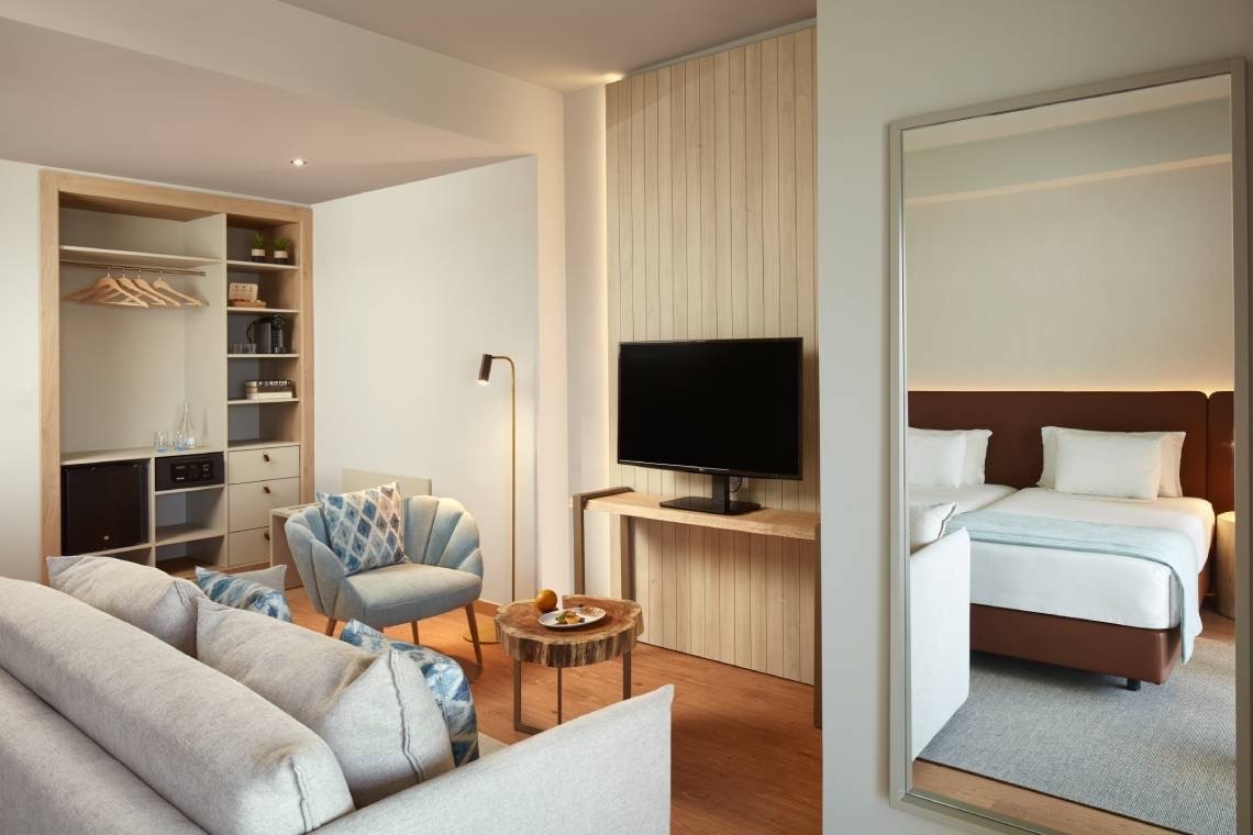 a hotel room with a couch a chair and a flat screen tv