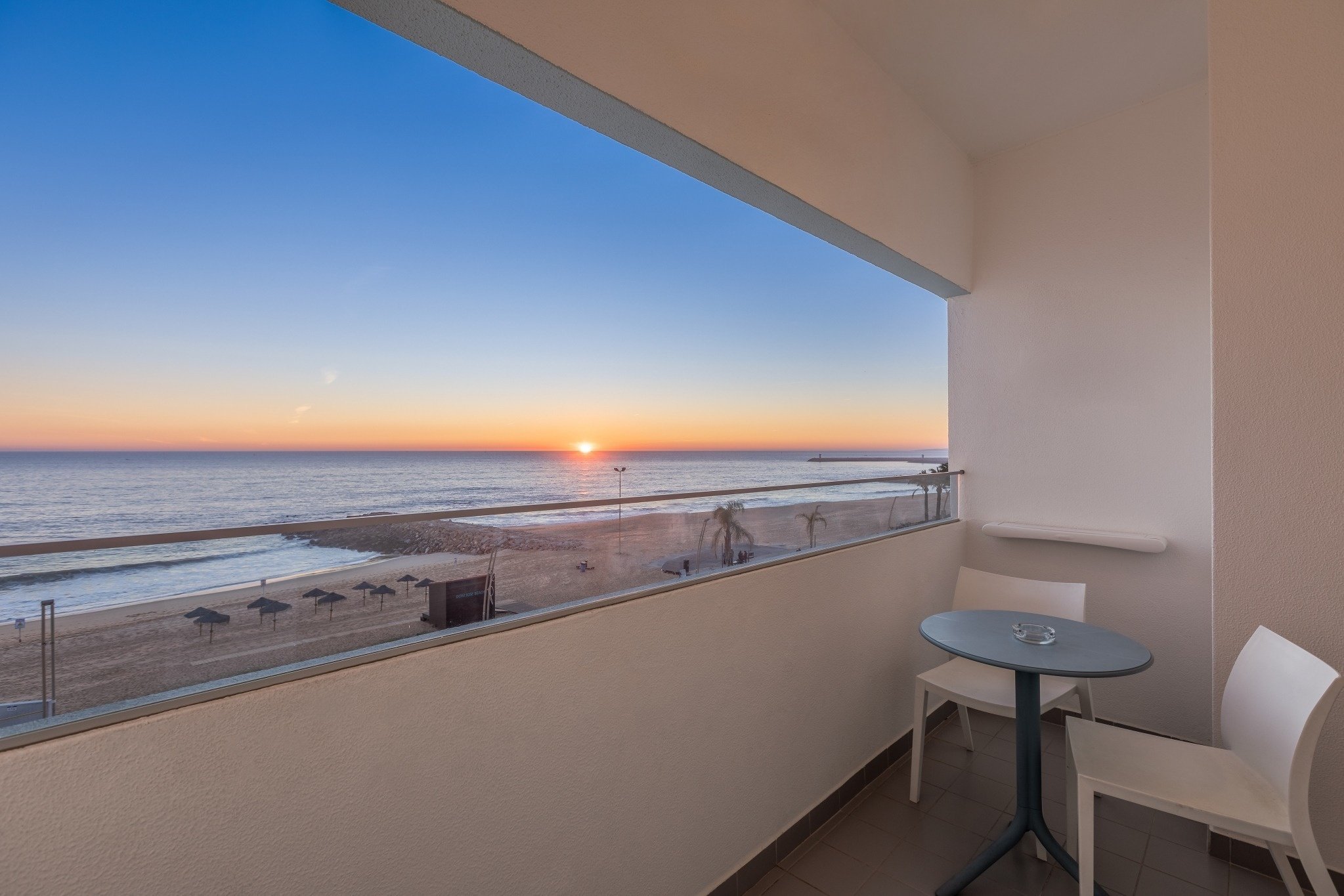 uma varanda com vista para o oceano ao pôr do sol