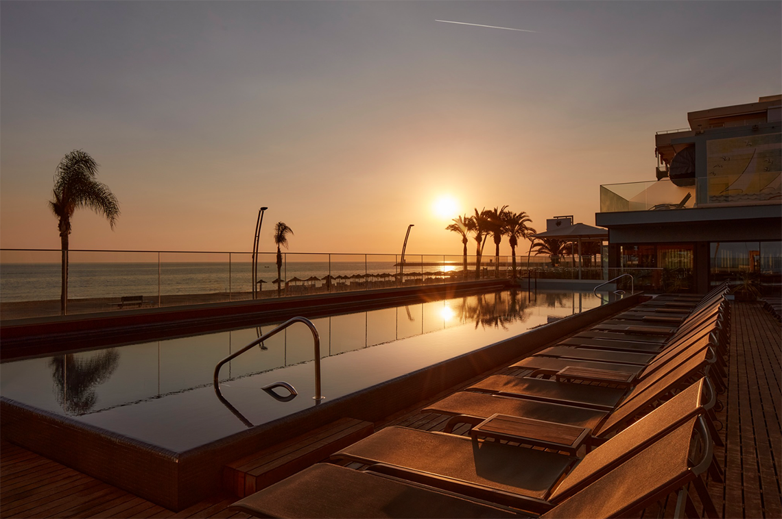uma piscina com vista para o oceano ao pôr do sol