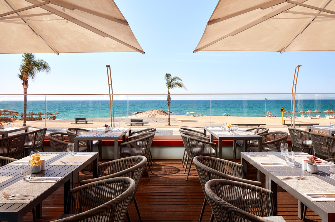 mesas e cadeiras em um restaurante com vista para o oceano
