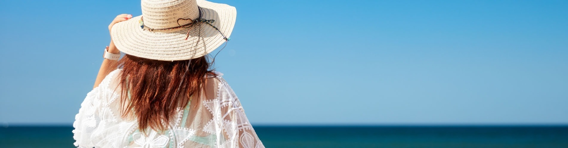 una mujer con un sombrero de paja está mirando el océano .