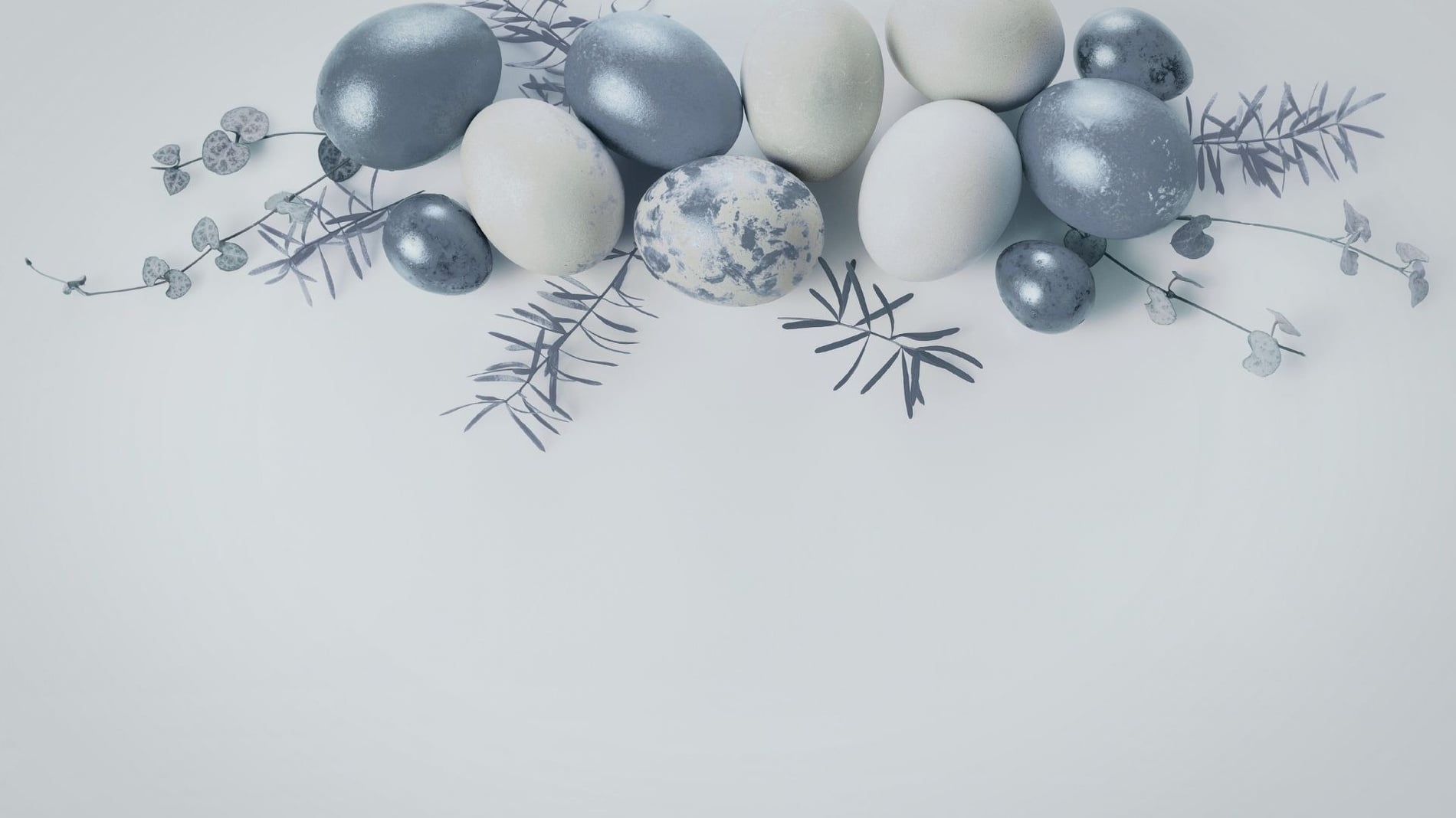 Ovos decorados em tons de cinza, branco e azul claro, intercalados com ramos e folhagens, estão dispostos artisticamente na parte superior de um fundo branco minimalista.