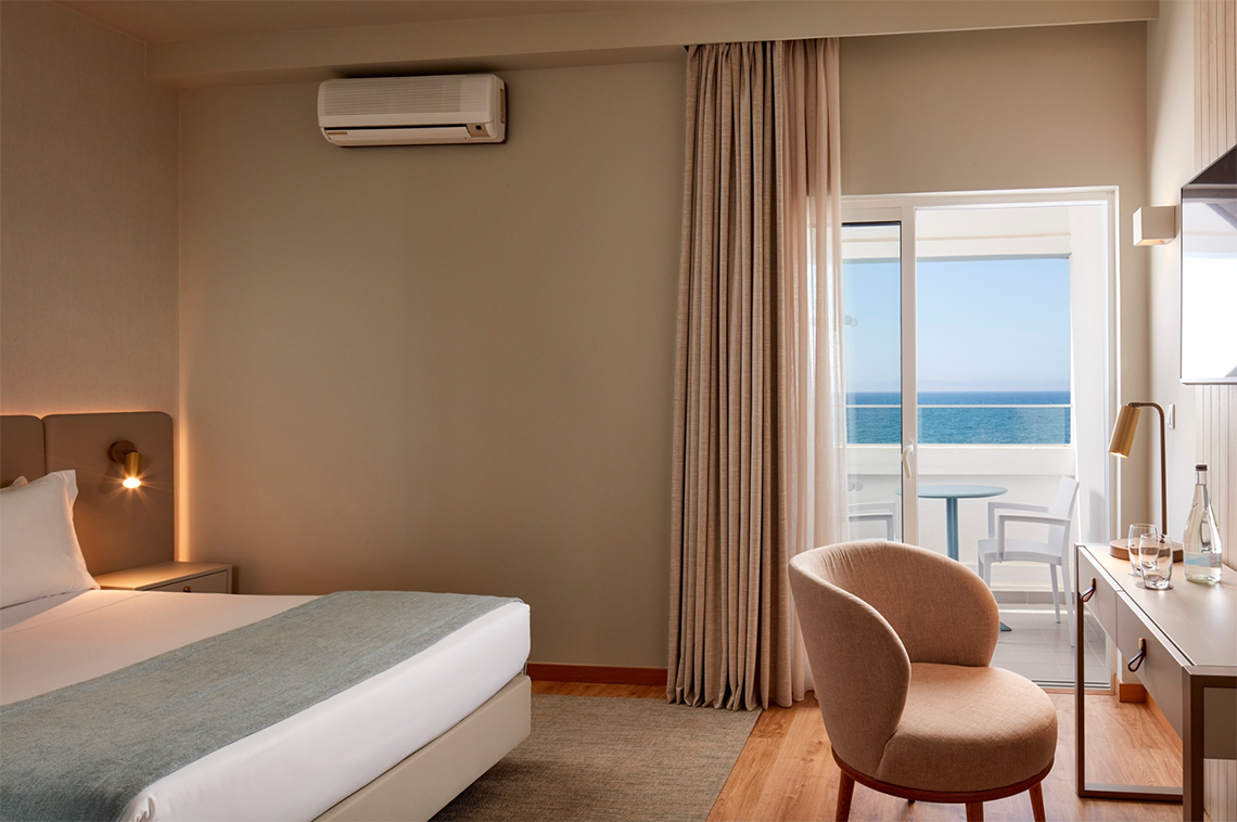 um quarto com cama , cadeira e mesa com vista para o oceano