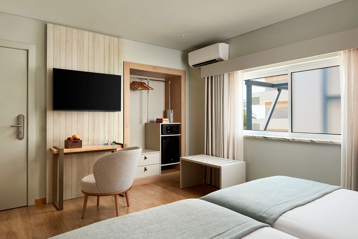 Chambre d'hôtel moderne avec lit, TV et placard. Idéal pour votre Dom José Beach Hotel.