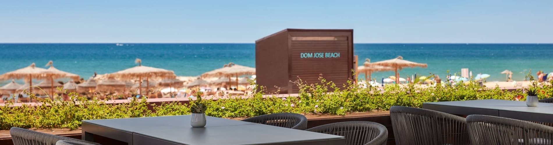 tables and chairs in front of a kiosk that says dom jose beach