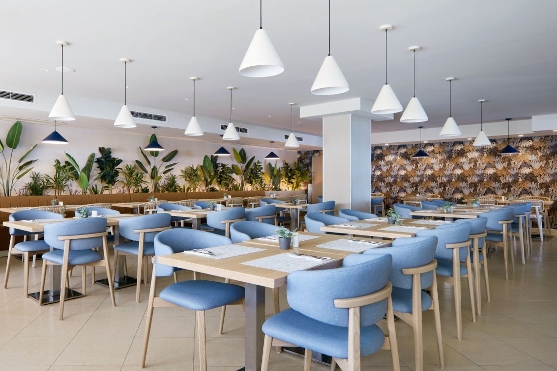Stylish dining area at Dom Jose Beach Hotel with blue chairs and modern lighting.