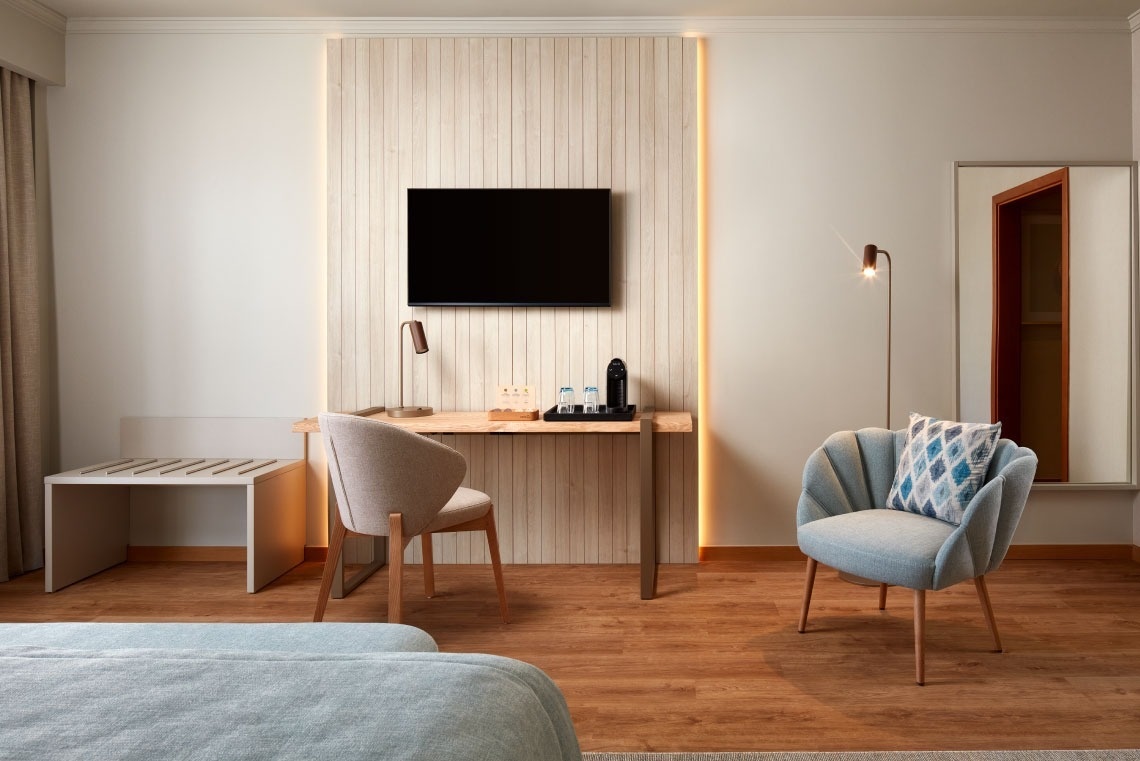 a hotel room with a chair a desk and a flat screen tv