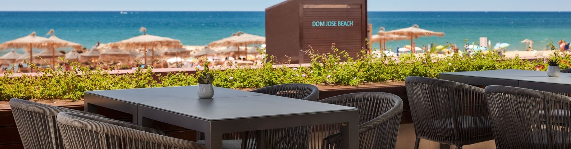 tables and chairs in front of a sign that says dom jose beach