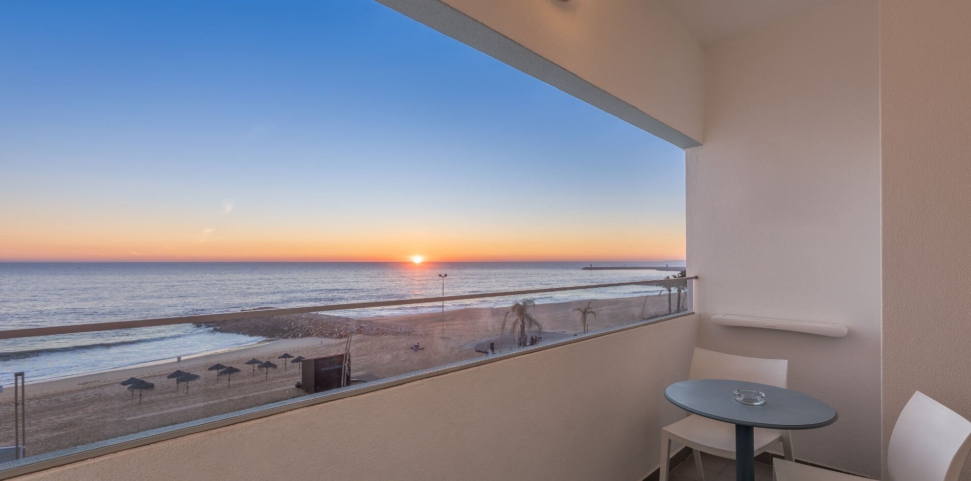 uma varanda com vista para o oceano ao pôr do sol