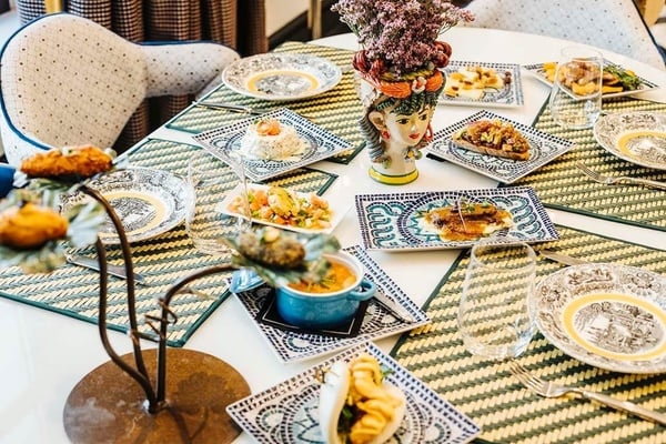 a table with plates of food and a vase with flowers on it