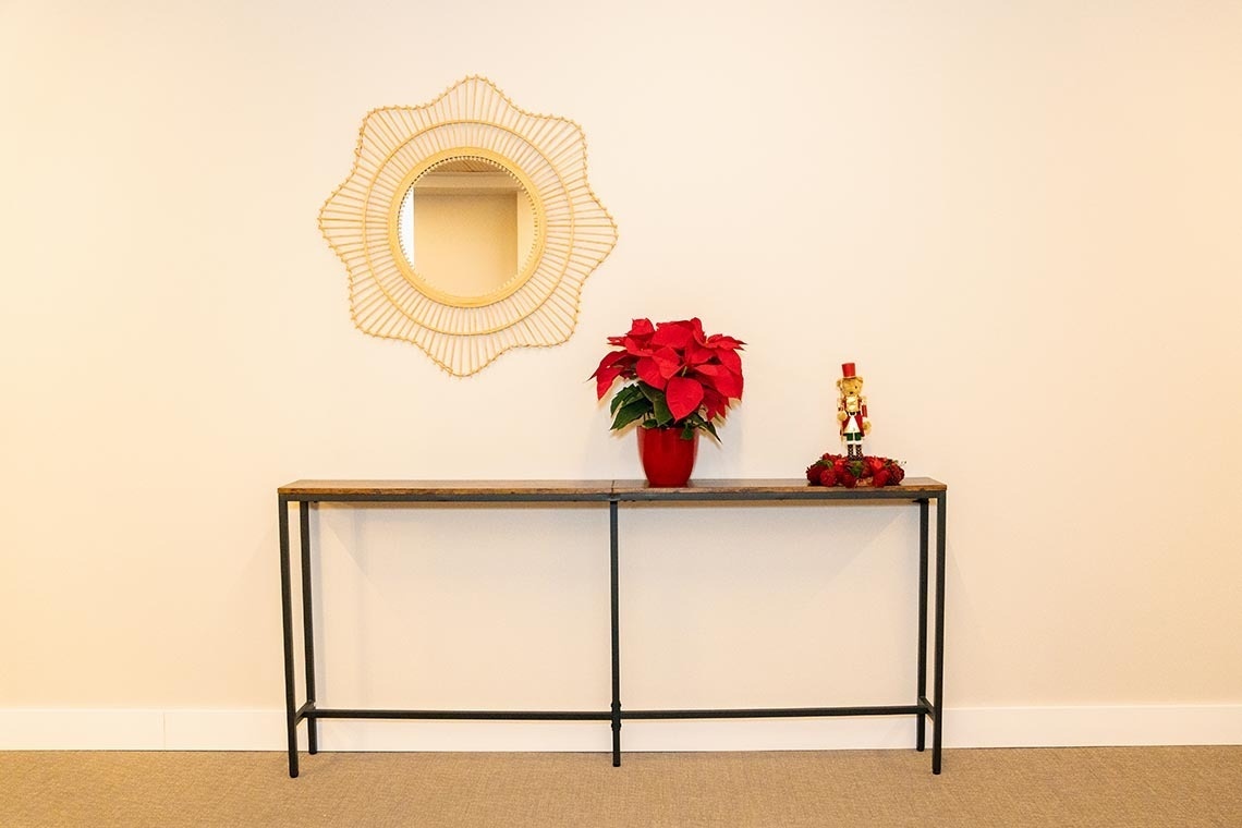 una mesa con una flor roja y un espejo en la pared