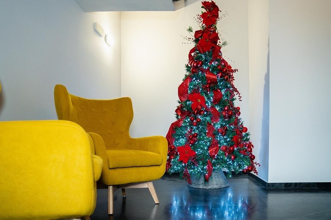 un árbol de navidad está decorado en rojo y verde junto a una silla amarilla