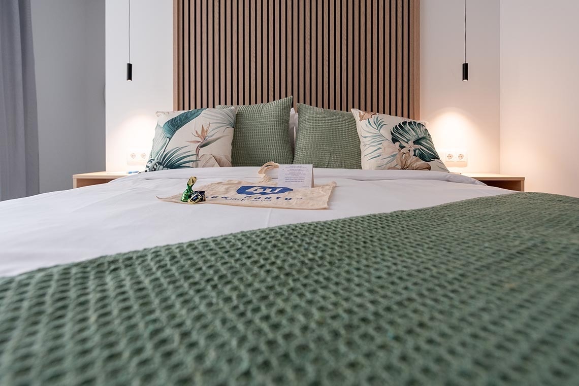 una habitación con una cama blanca y una manta verde