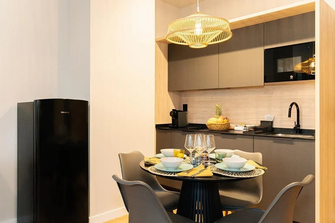 una cocina con una mesa y sillas y una nevera negra