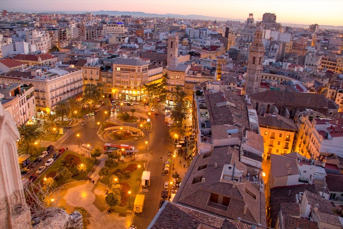 an aerial view of a city at night with a green bus in the middle