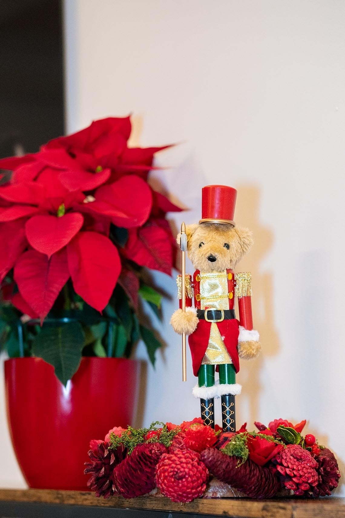 un cascanueces de peluche está sentado encima de una corona de flores rojas