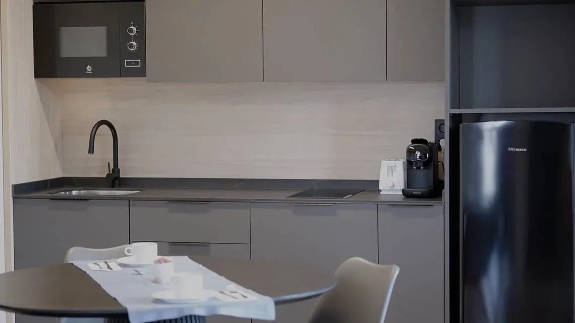 una cocina con gabinetes grises y una nevera hisense negra