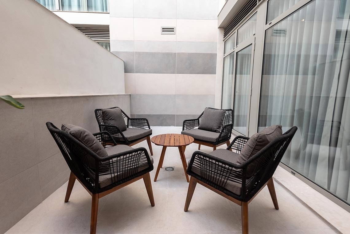 un pequeño patio con sillas y una mesa de madera