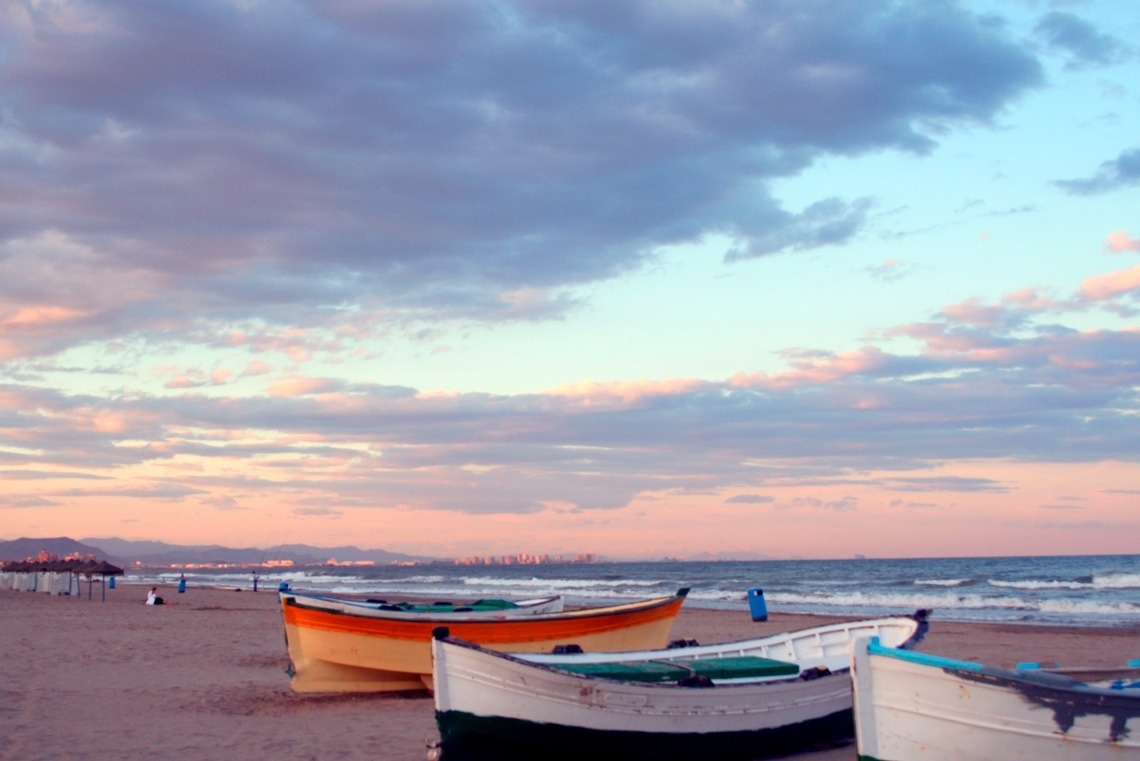 several boats are lined up on the beach at sunset