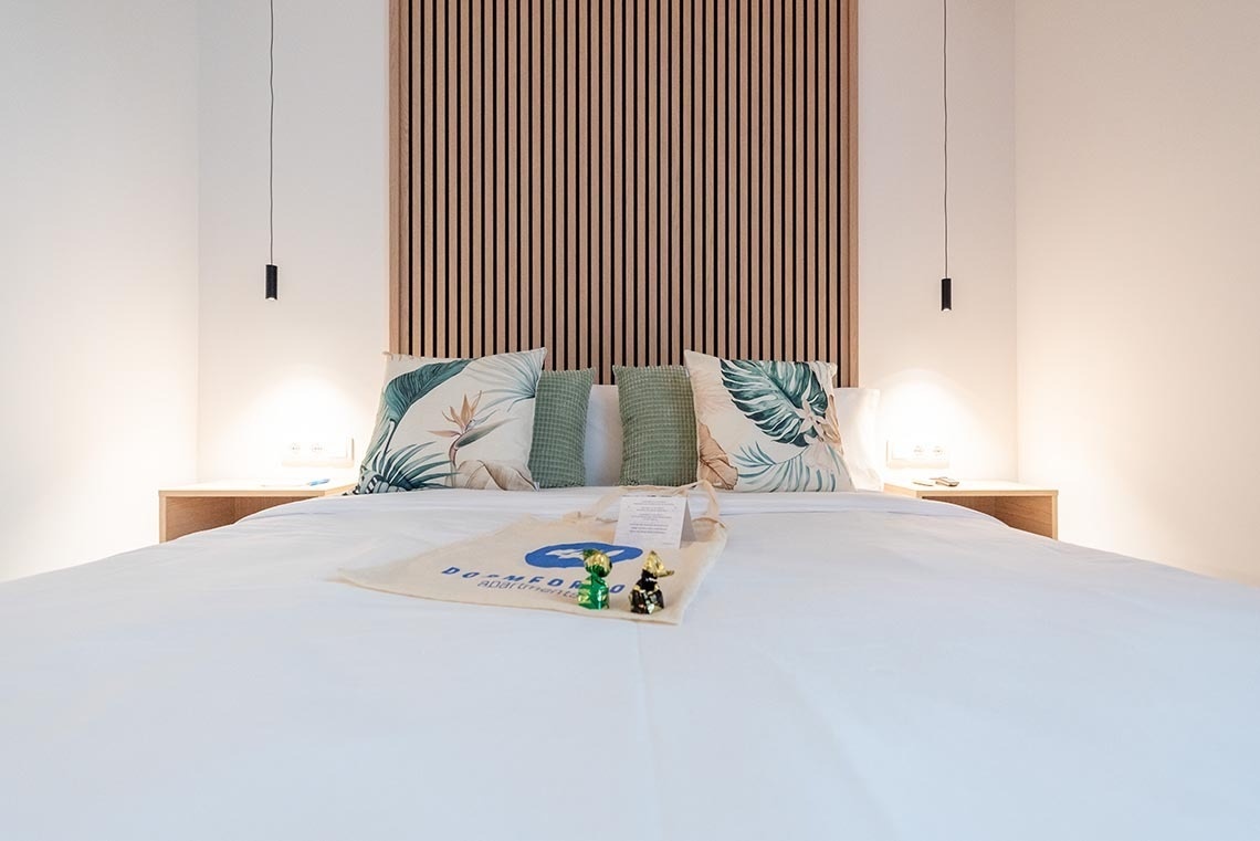 una habitación con una cama blanca y almohadas y una bolsa con la palabra bufanda encima