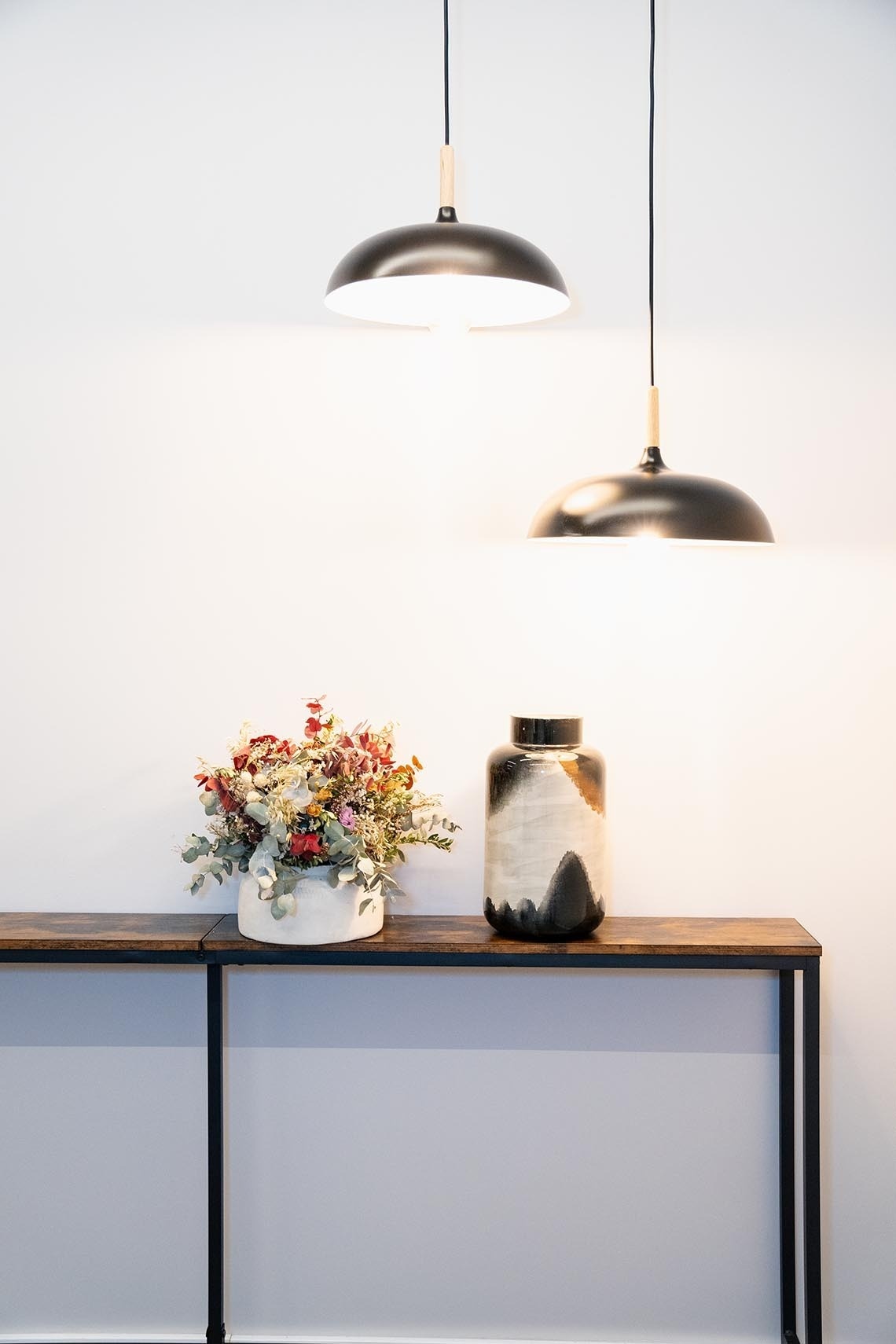 una mesa de madera con dos lámparas y un jarrón de flores