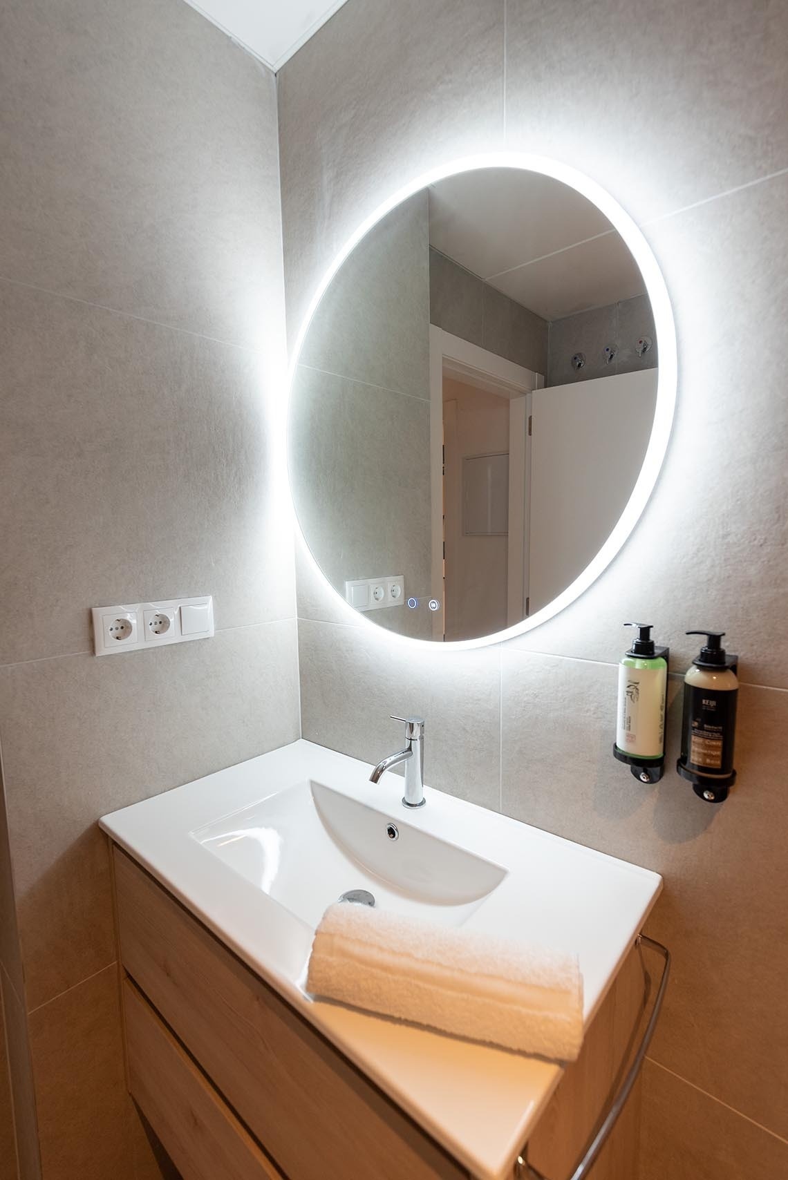 un baño con un lavabo y un espejo redondo