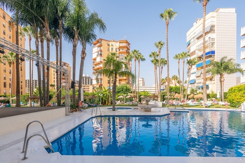 una piscina rodeada de palmeras en un complejo de apartamentos