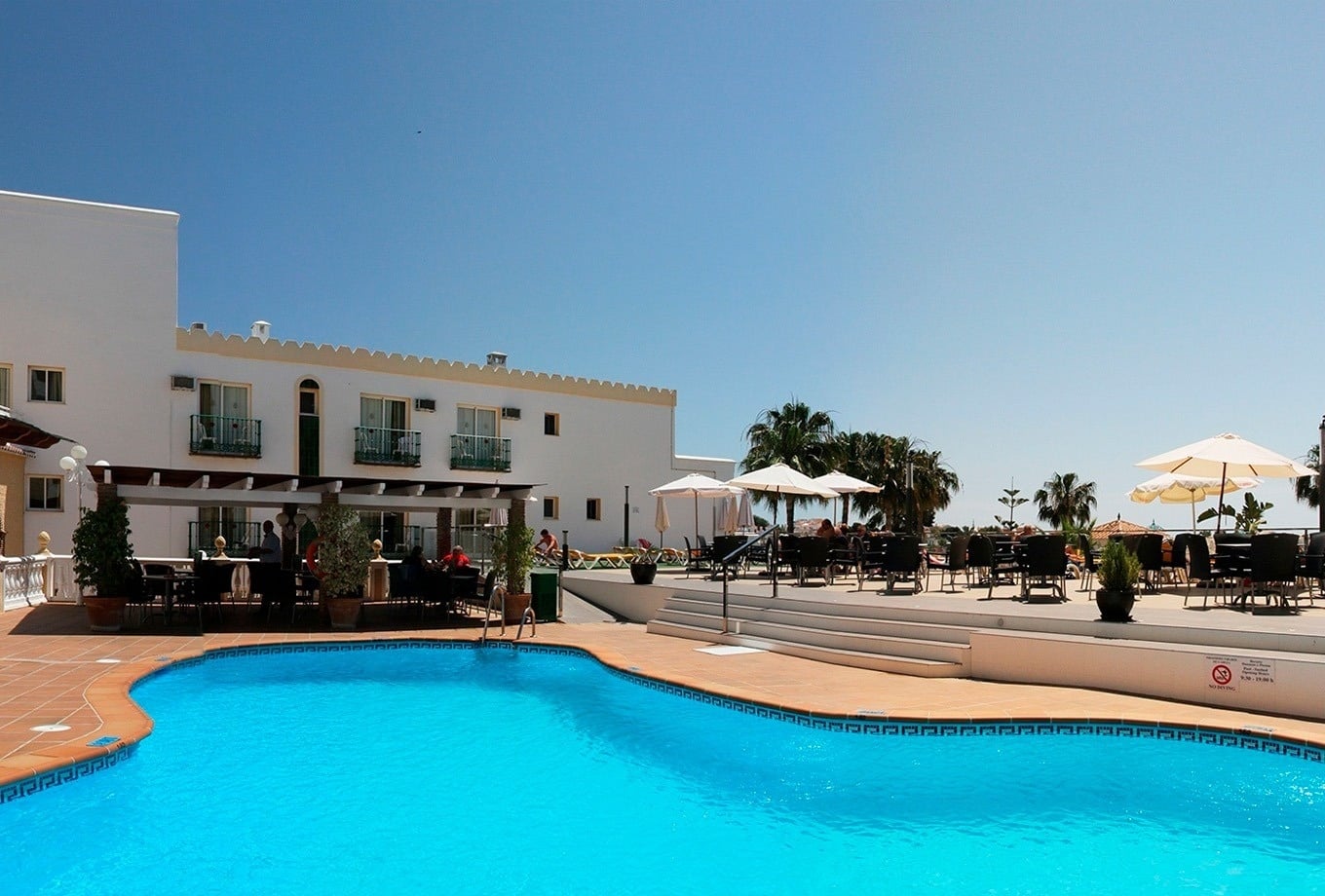 Piscina y palmeras en hotel, ideal para Dorobe vacacional.