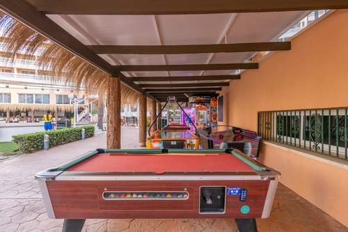 a pool table under a canopy with a machine that says ' arcade ' on it