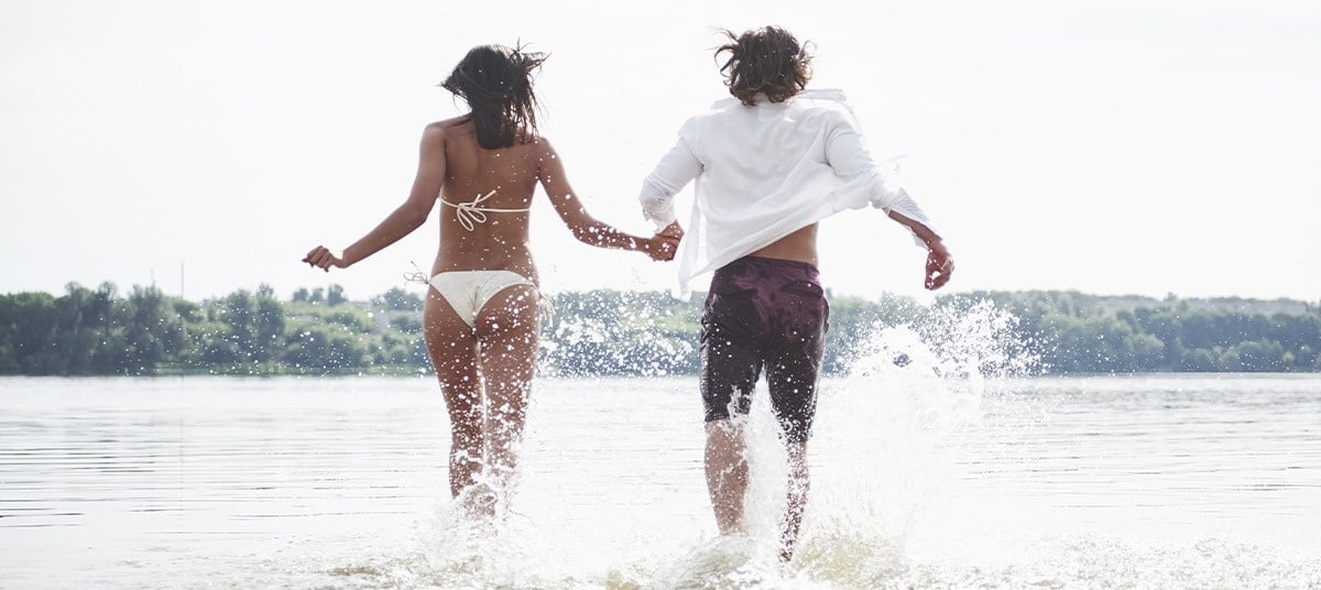 a man and a woman with backpacks are standing on top of a hill with their arms outstretched