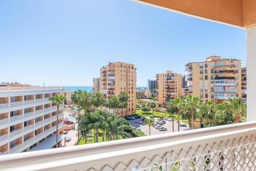 a view of a city from a balcony with palm trees in the foreground