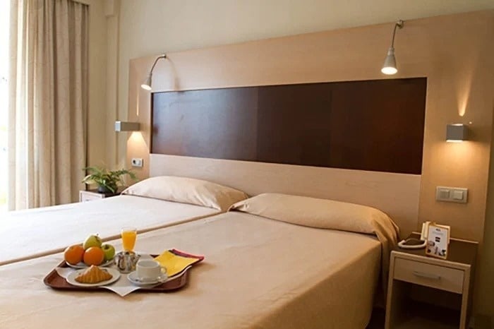 a hotel room with two beds and a tray of food on the bed