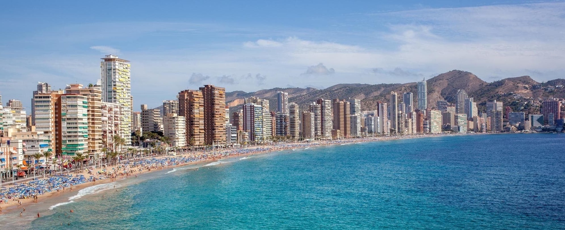 una playa con muchos edificios altos y montañas en el fondo