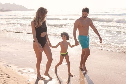 a family is walking on the beach holding hands .