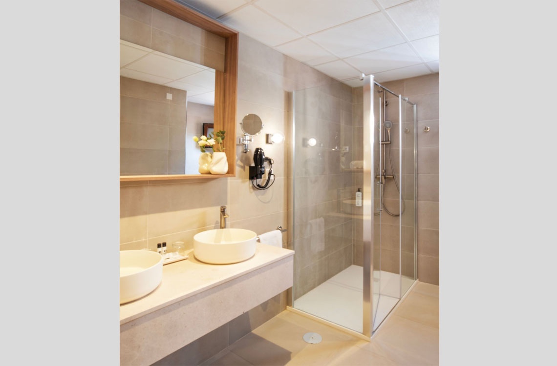 Elegante baño con ducha de cristal y lavabo doble, un toque de lujo en Dynastic Corporativa.