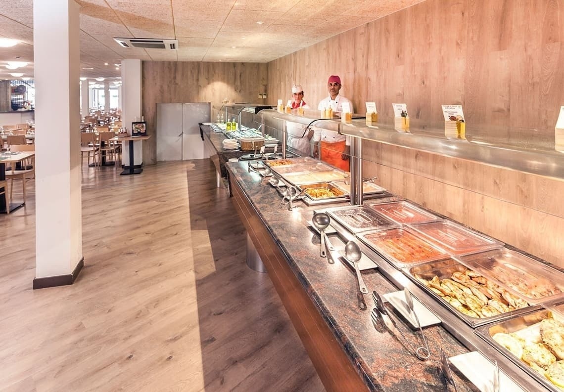 a buffet line in a restaurant with two chefs standing behind it