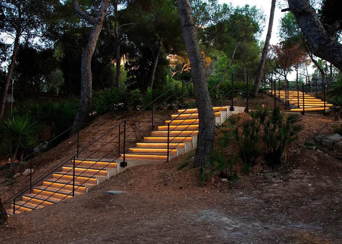 Dynastic Resorts hotel's warmly lit outdoor stairs winding through a serene, wooded evening landscape.