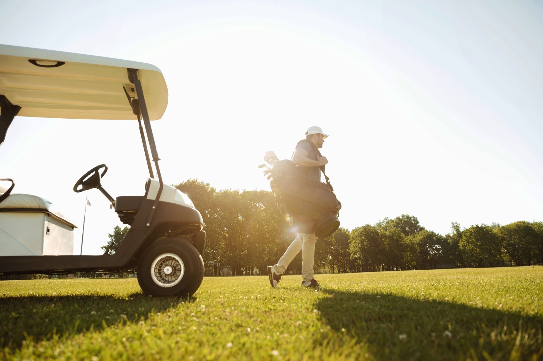 a man carrying a golf bag and a golf club on a golf course