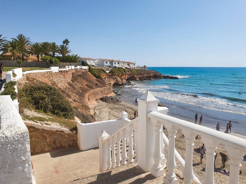 a view of a beach from a balcony with stairs leading up to it