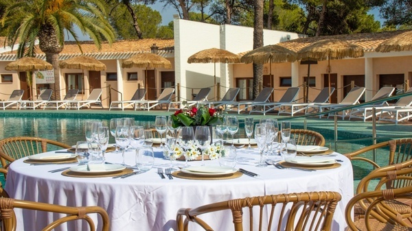una mesa con platos y copas junto a una piscina