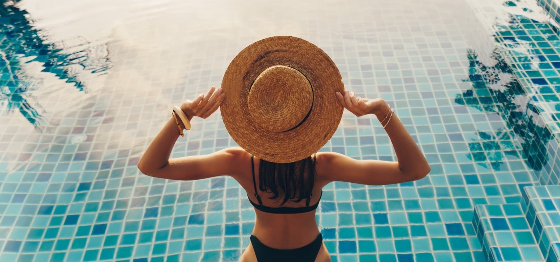 uma mulher de biquíni e chapéu está na piscina