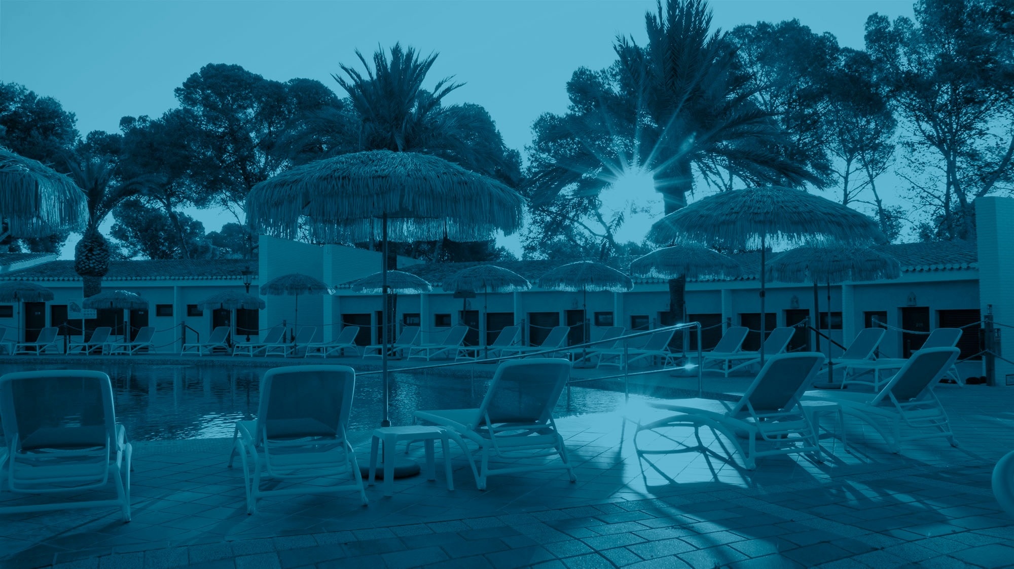 un grupo de sillas y sombrillas alrededor de una piscina