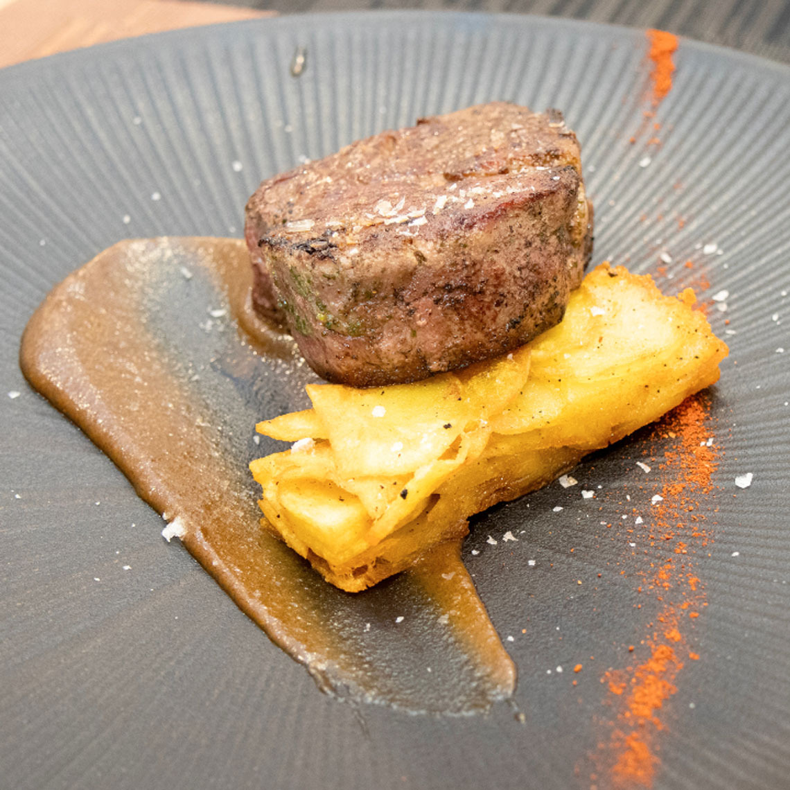 Exquisito solomillo Dynastic Resorts con patatas y salsa, una delicia de nuestro hotel.