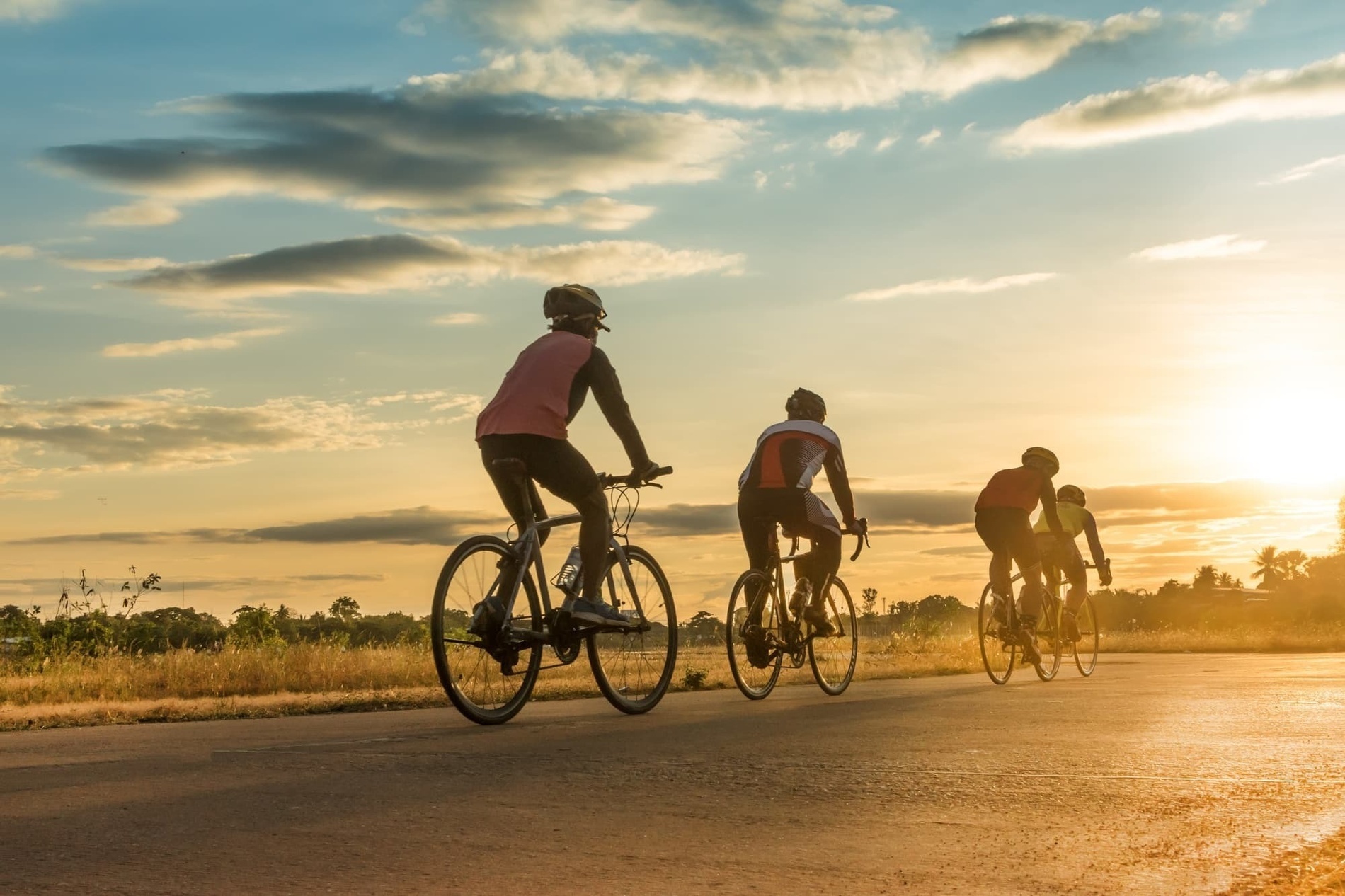 un grupo de personas en bicicleta por una carretera al atardecer