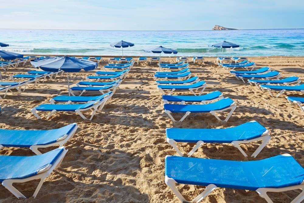 blue beach chairs and umbrellas on a sandy beach