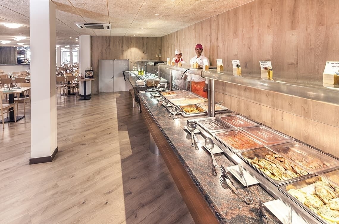 a buffet line in a restaurant with two chefs standing behind it