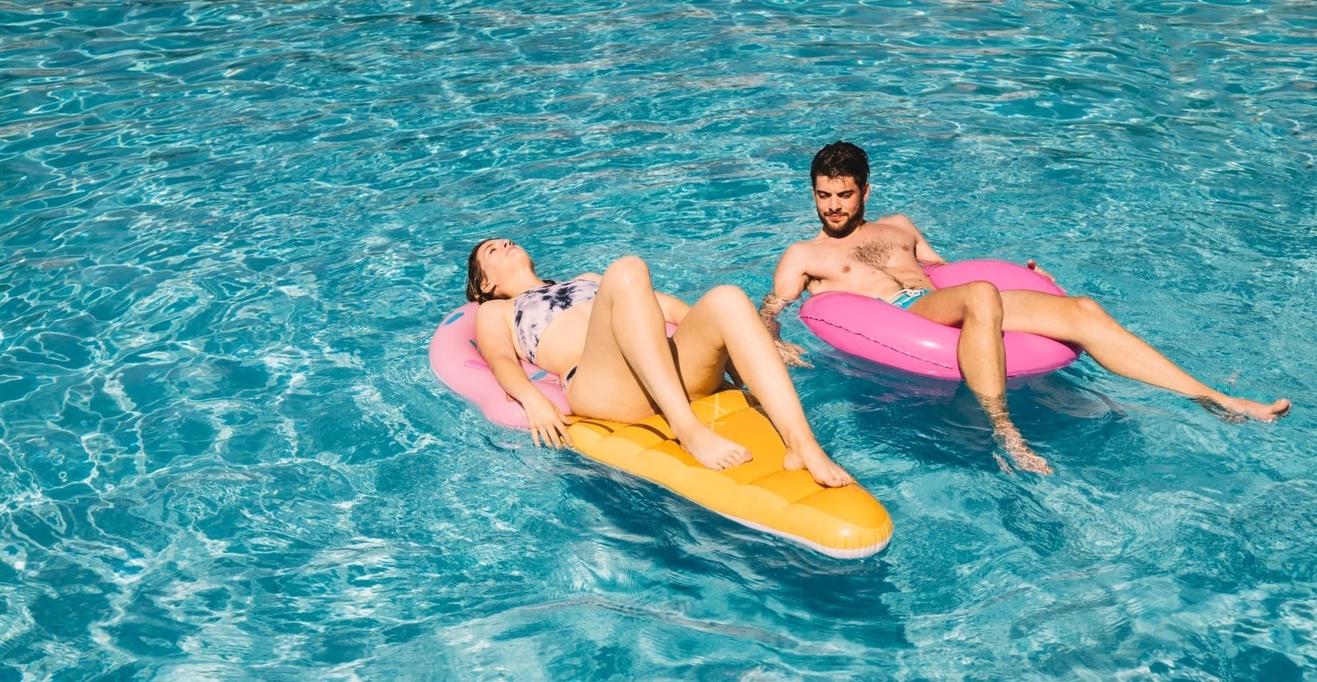 un hombre y una mujer flotan en anillos inflables en una piscina