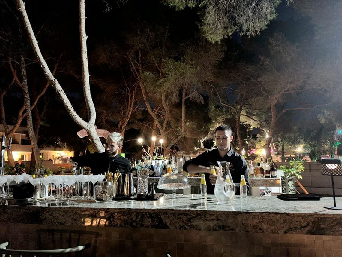 Outdoor hotel bar at Dynastic Resorts. Bartenders create cocktails under the night sky.