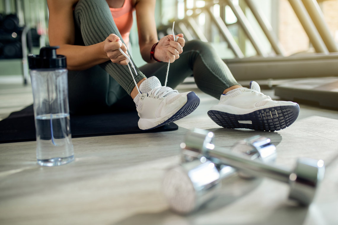 Fitness enthusiast tying shoes in gym Dynastic Resorts.