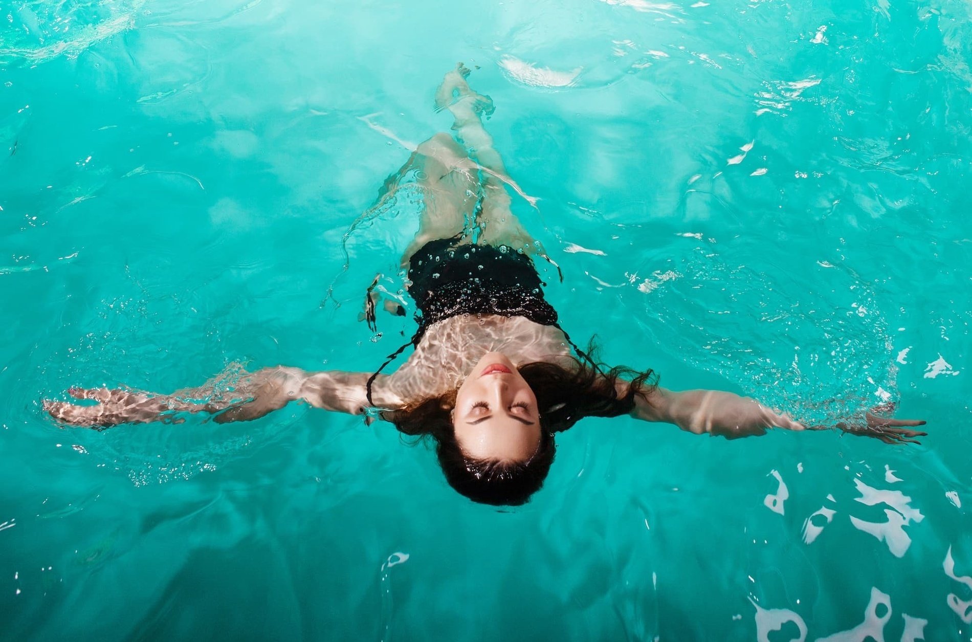 a woman is swimming in a pool with her eyes closed